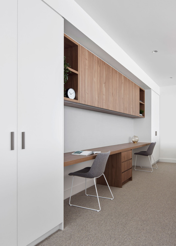 Medium sized contemporary home office in Melbourne with white walls, carpet and a built-in desk.