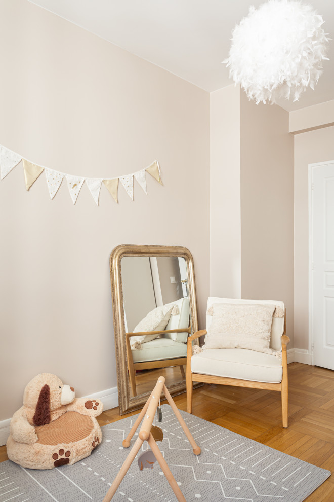 Réalisation d'une chambre de bébé neutre minimaliste de taille moyenne avec un mur beige et parquet clair.