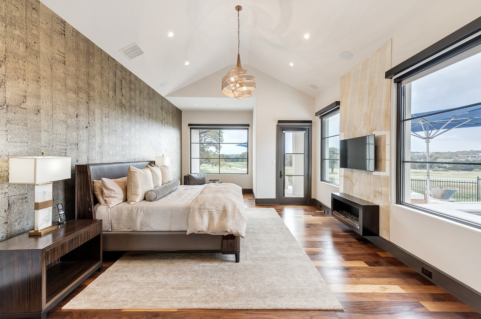 This is an example of a mid-sized contemporary master bedroom in Orange County with white walls, medium hardwood floors, a standard fireplace, a stone fireplace surround and brown floor.