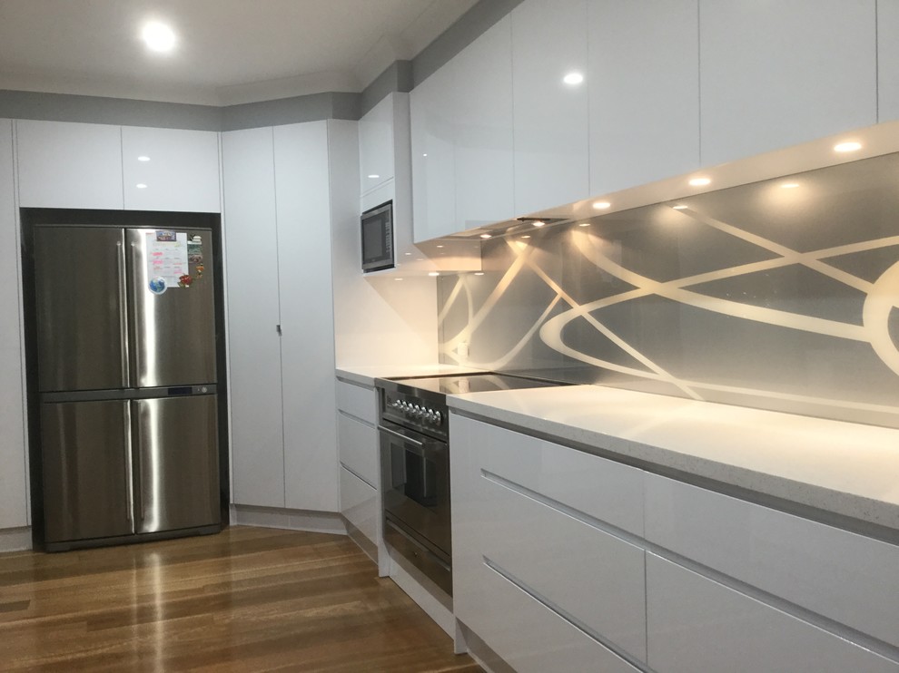 Small contemporary single-wall eat-in kitchen in Sydney with an undermount sink, multi-coloured splashback, glass sheet splashback, stainless steel appliances and with island.