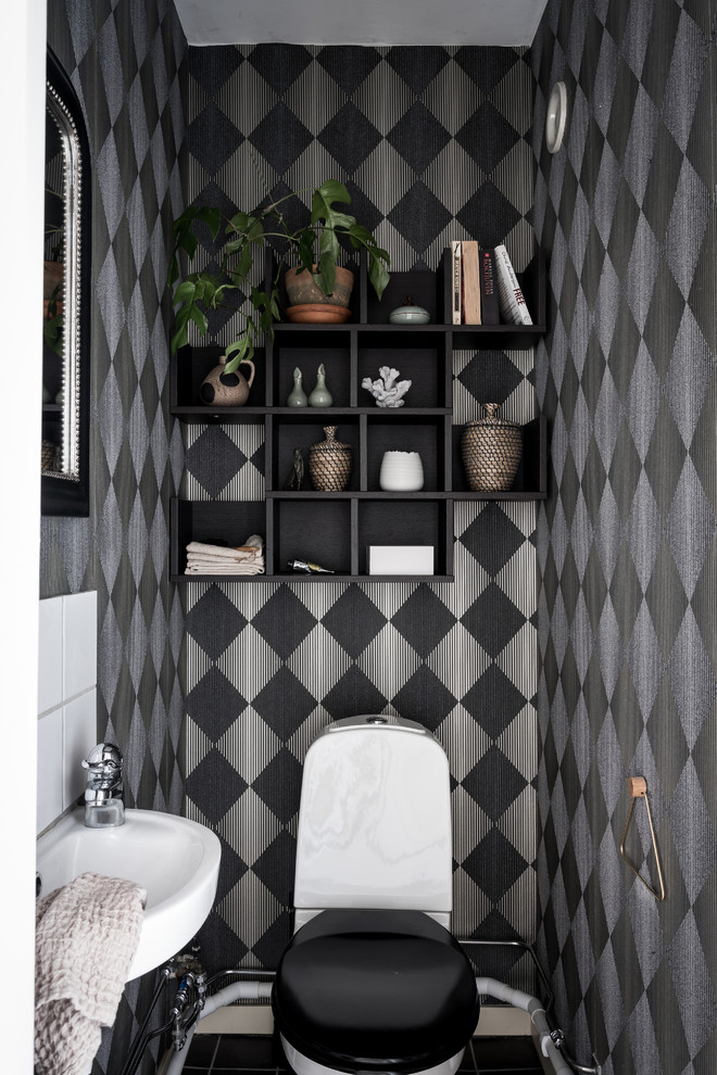 Scandinavian powder room in Gothenburg with a two-piece toilet, multi-coloured walls, a wall-mount sink and black floor.