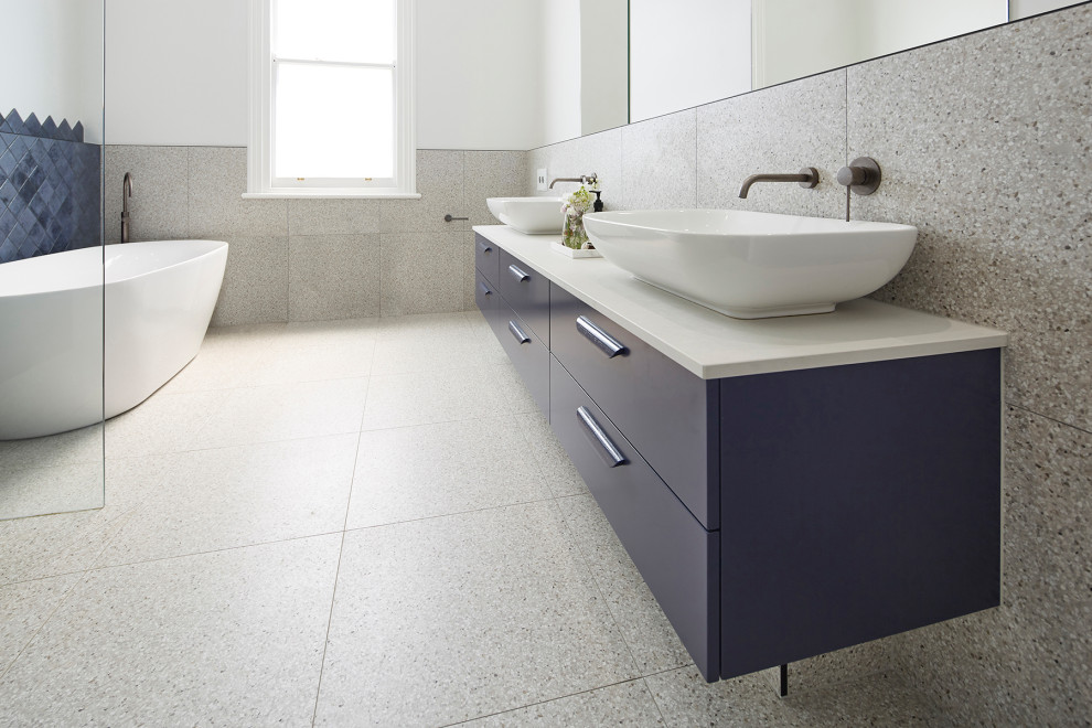 Design ideas for a large modern kids bathroom in Melbourne with blue cabinets, a freestanding tub, an open shower, a wall-mount toilet, gray tile, multi-coloured walls, terrazzo floors, a vessel sink, engineered quartz benchtops, multi-coloured floor, an open shower, white benchtops, furniture-like cabinets and stone tile.