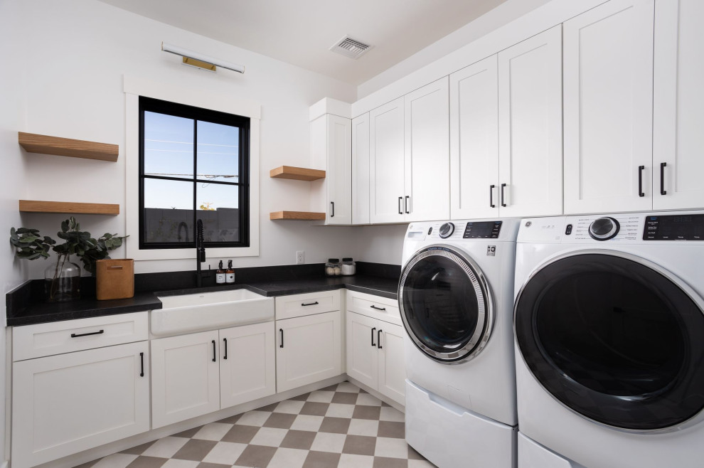 Inspiration for a large u-shaped dedicated laundry room in Phoenix with a farmhouse sink, shaker cabinets, white cabinets, white walls, a side-by-side washer and dryer and black benchtop.