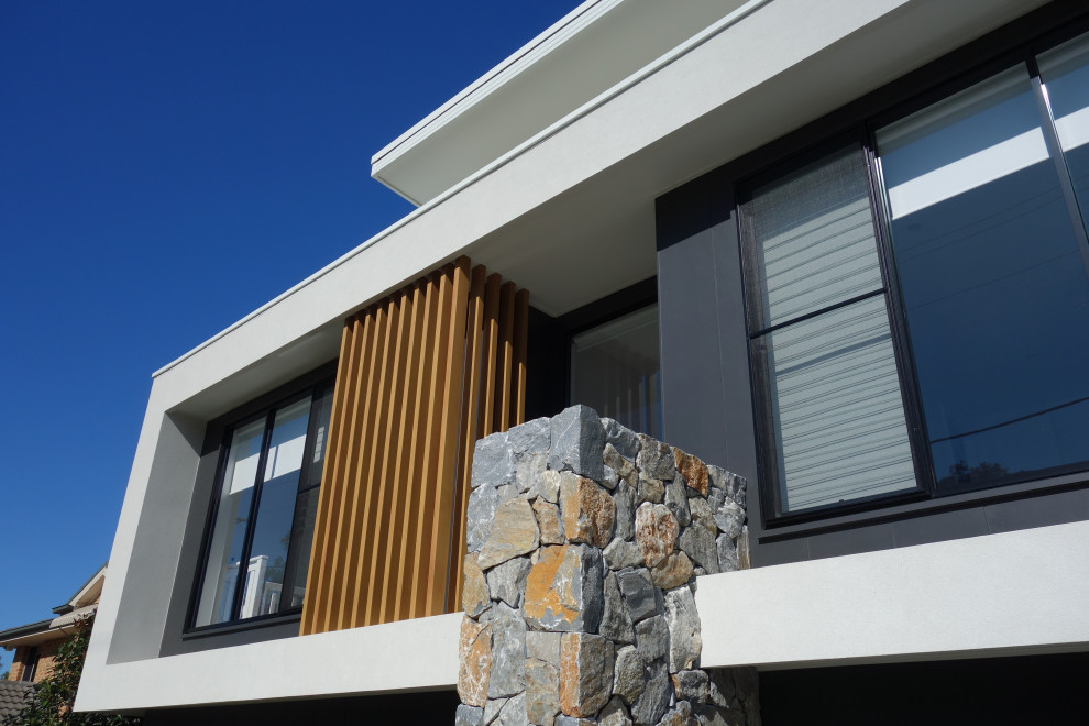 Inspiration for a large modern two-storey black house exterior in Wollongong with a flat roof and a metal roof.
