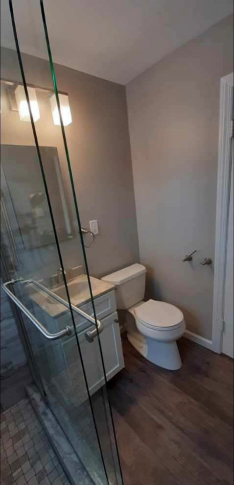 Inspiration for a small modern master bathroom in New York with shaker cabinets, white cabinets, a double shower, a two-piece toilet, beige tile, ceramic tile, beige walls, laminate floors, an integrated sink, brown floor, a sliding shower screen, beige benchtops, a single vanity and a freestanding vanity.