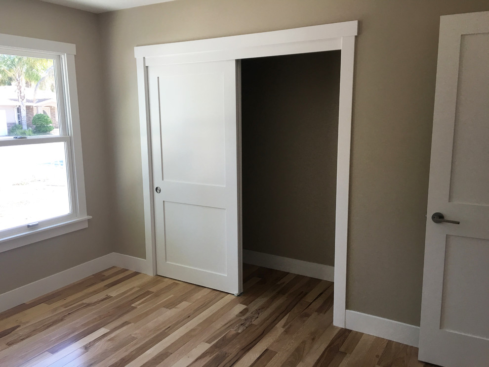 Mid-sized traditional gender-neutral built-in wardrobe in San Francisco with flat-panel cabinets, white cabinets and light hardwood floors.