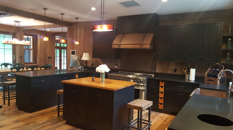 Photo of a large country l-shaped eat-in kitchen in New York with beaded inset cabinets, granite benchtops, beige splashback, stainless steel appliances, medium hardwood floors, with island, brown floor and black cabinets.