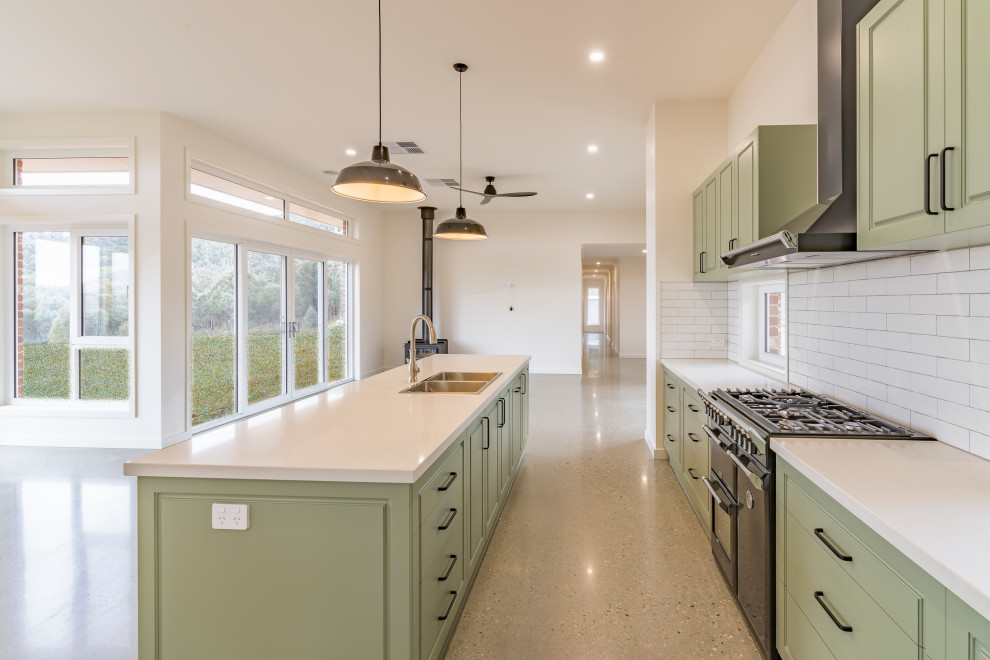 Design ideas for a large contemporary galley kitchen pantry in Other with a built-in sink, recessed-panel cabinets, green cabinets, engineered stone countertops, white splashback, ceramic splashback, black appliances, concrete flooring, an island, grey floors and white worktops.