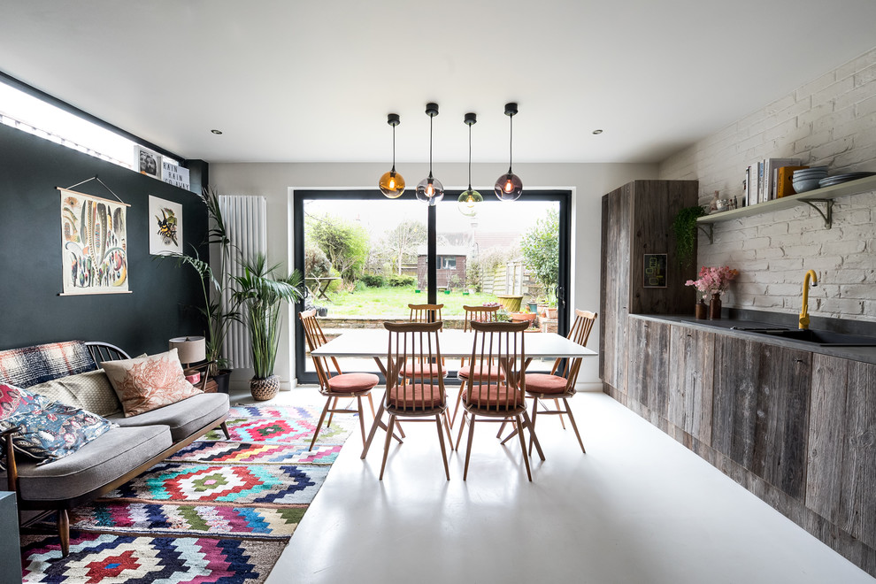 Mid-sized eclectic single-wall open plan kitchen in London with a single-bowl sink, flat-panel cabinets, medium wood cabinets, concrete benchtops, white splashback, brick splashback, stainless steel appliances, concrete floors, with island, white floor and grey benchtop.