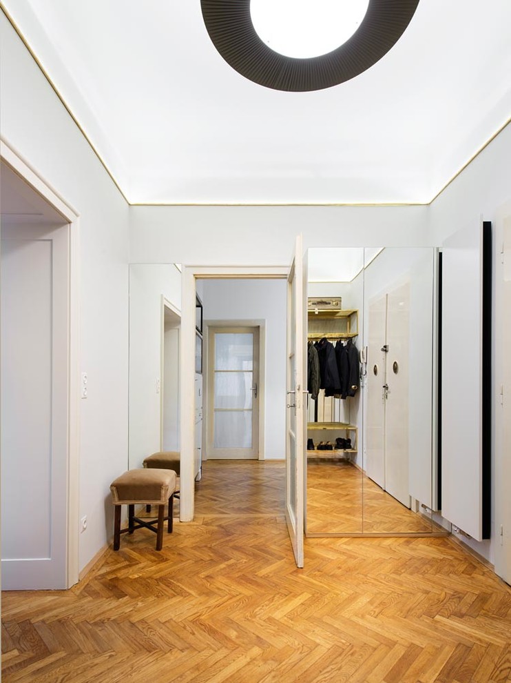 This is an example of a mid-sized contemporary entry hall in Munich with white walls, medium hardwood floors, a single front door and a glass front door.