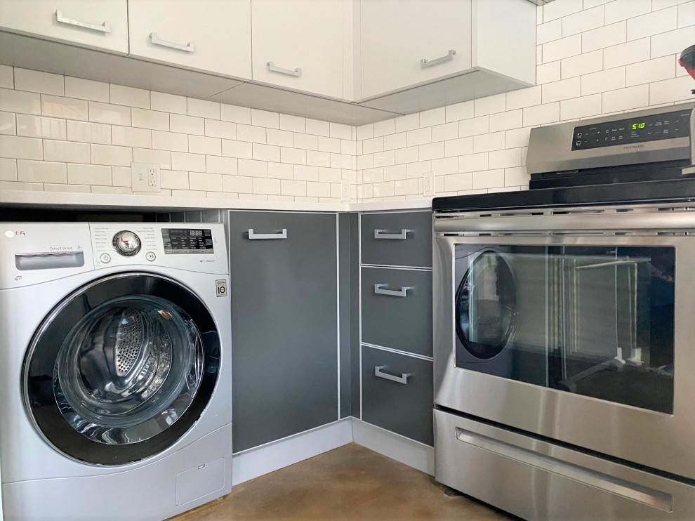 Small contemporary u-shaped laundry room in Portland with a farmhouse sink, flat-panel cabinets, grey cabinets, quartz benchtops, white splashback, subway tile splashback, concrete floors, beige floor and white benchtop.