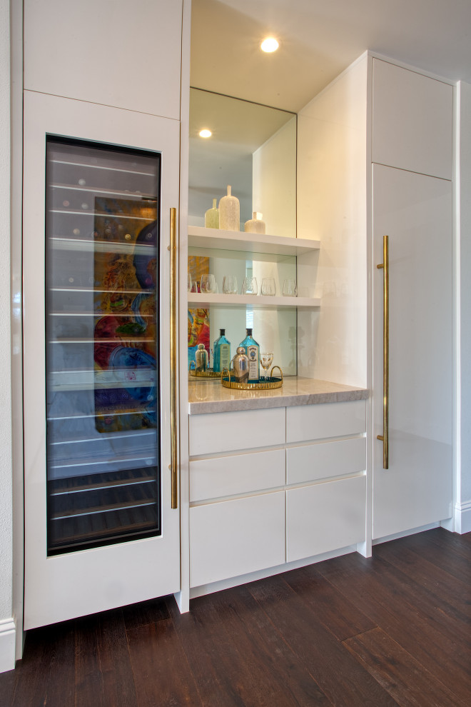 Photo of a modern wet bar in San Francisco with flat-panel cabinets, white cabinets, quartzite benchtops, glass sheet splashback and dark hardwood floors.