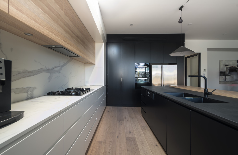 This is an example of a mid-sized modern l-shaped eat-in kitchen in Melbourne with flat-panel cabinets, medium wood cabinets, marble benchtops and with island.
