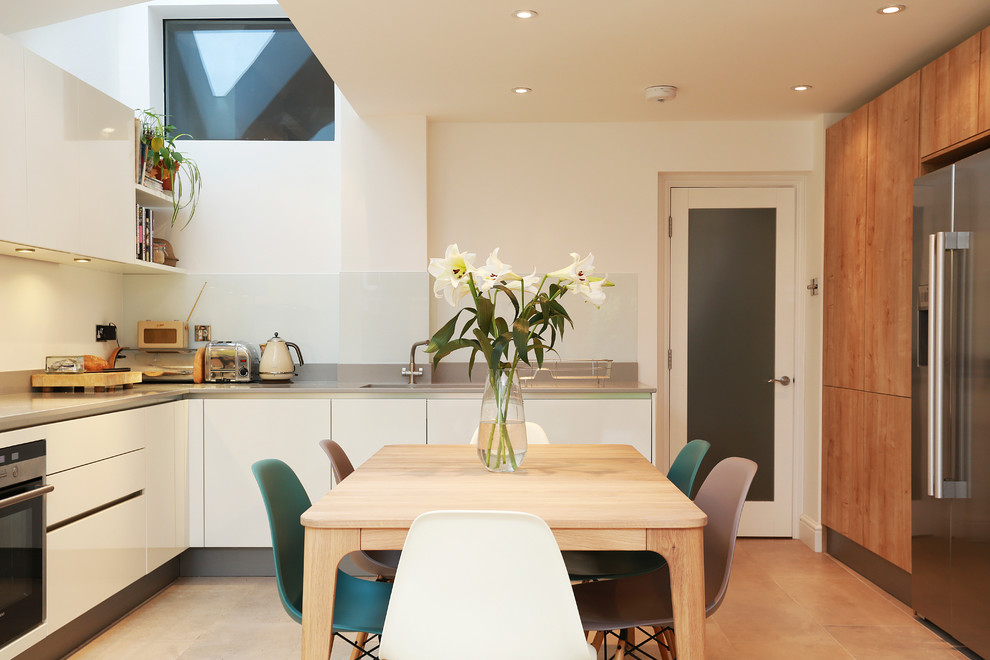 Large contemporary open plan kitchen in London with a drop-in sink, flat-panel cabinets, medium wood cabinets, quartz benchtops, yellow splashback, glass sheet splashback, panelled appliances, no island and beige floor.