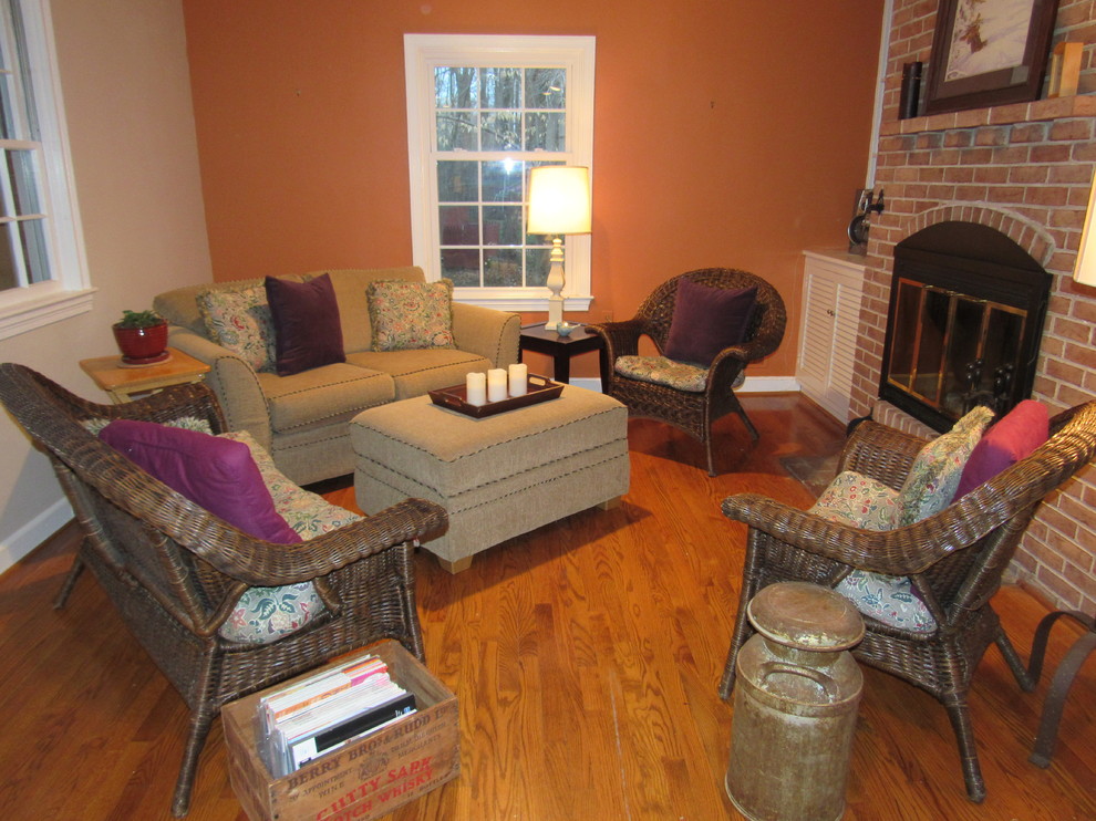 This is an example of a mid-sized eclectic open concept living room in Philadelphia with orange walls, medium hardwood floors, a standard fireplace, a brick fireplace surround and no tv.