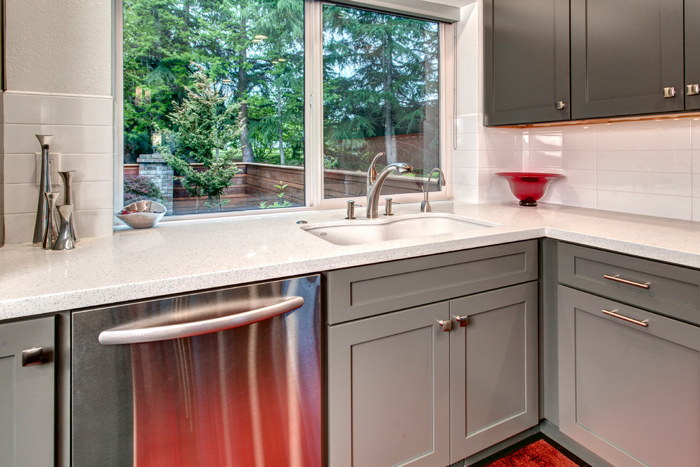 Example of a mid-sized minimalist l-shaped dark wood floor eat-in kitchen design in Seattle with an undermount sink, shaker cabinets, gray cabinets, quartz countertops, white backsplash, stainless steel appliances and an island