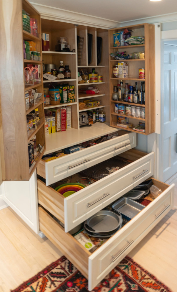Photo of a mid-sized transitional galley kitchen pantry in New York with raised-panel cabinets, white cabinets, wood benchtops, light hardwood floors, beige floor and white benchtop.