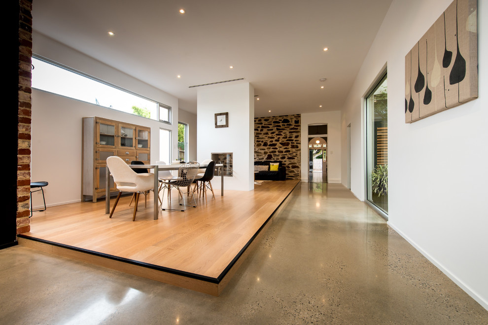 This is an example of a modern dining room in Adelaide with white walls and concrete floors.