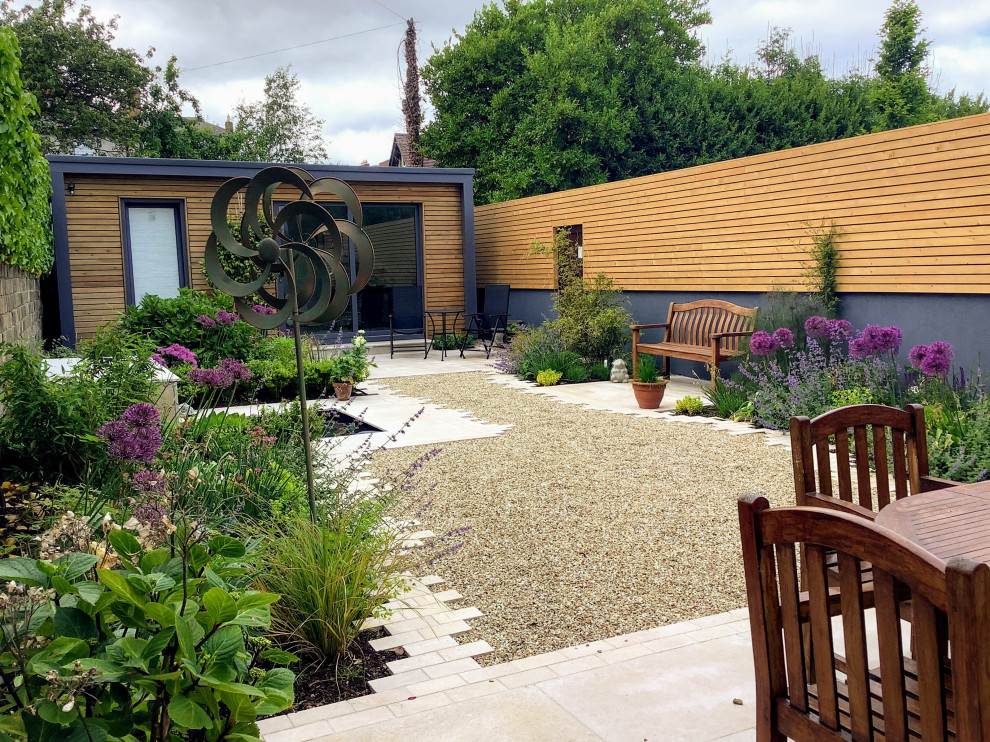 На фото: маленький участок и сад в современном стиле с дорожками, покрытием из каменной брусчатки и с деревянным забором для на участке и в саду с