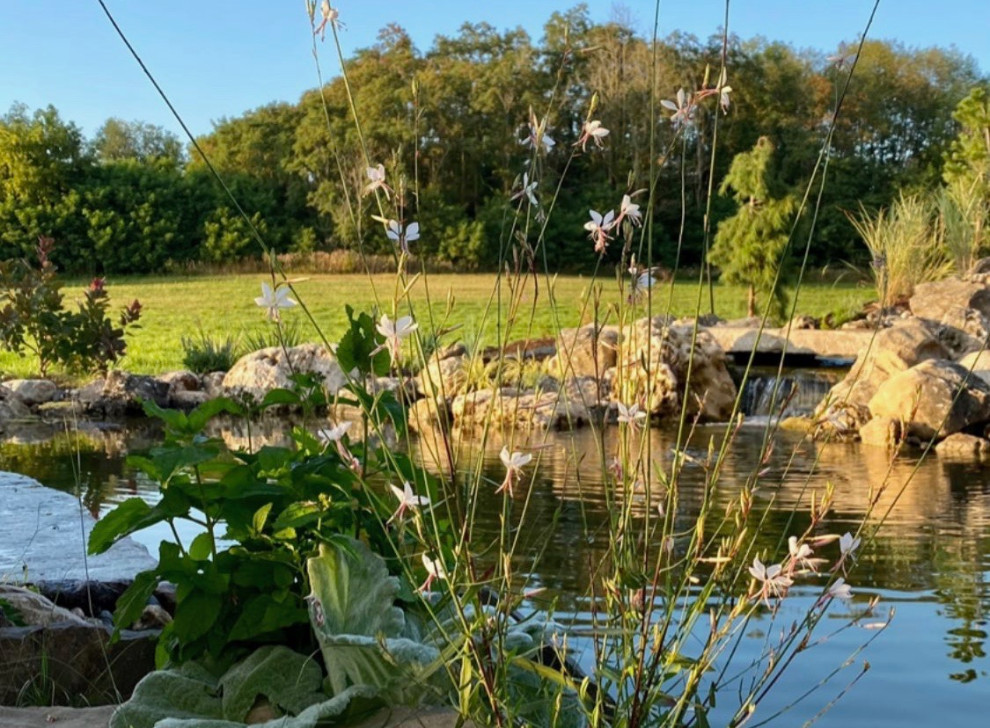 Cette photo montre un grand piscine avec aménagement paysager nature en forme de haricot avec une cour et des pavés en pierre naturelle.