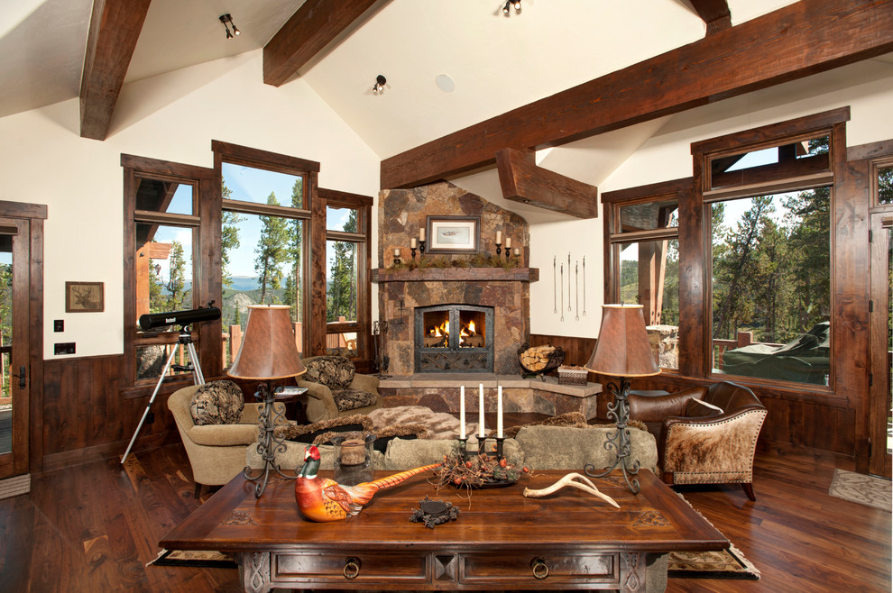 Country living room in Denver with dark hardwood floors, a corner fireplace and a stone fireplace surround.