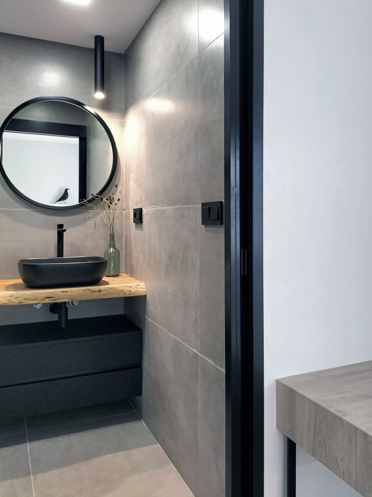 Idéer för att renovera ett litet funkis en-suite badrum, med svarta skåp, en vägghängd toalettstol, grå kakel, grå väggar, klinkergolv i porslin, ett fristående handfat, träbänkskiva, grått golv och dusch med skjutdörr
