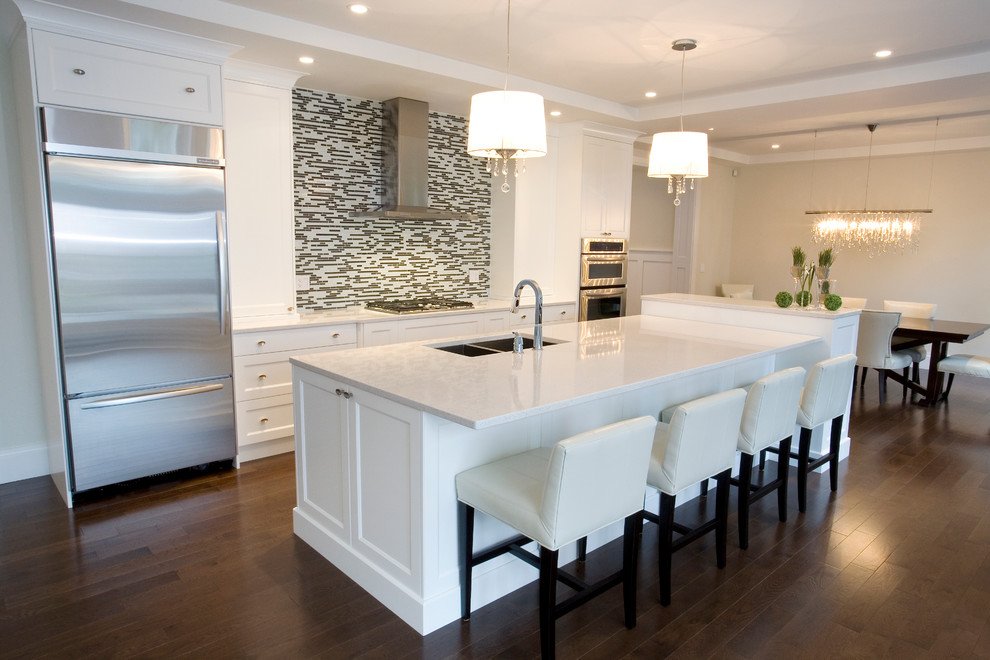 Eat-in kitchen - large transitional medium tone wood floor eat-in kitchen idea in Calgary with an undermount sink, recessed-panel cabinets, white cabinets, quartz countertops, multicolored backsplash, mosaic tile backsplash, stainless steel appliances and an island