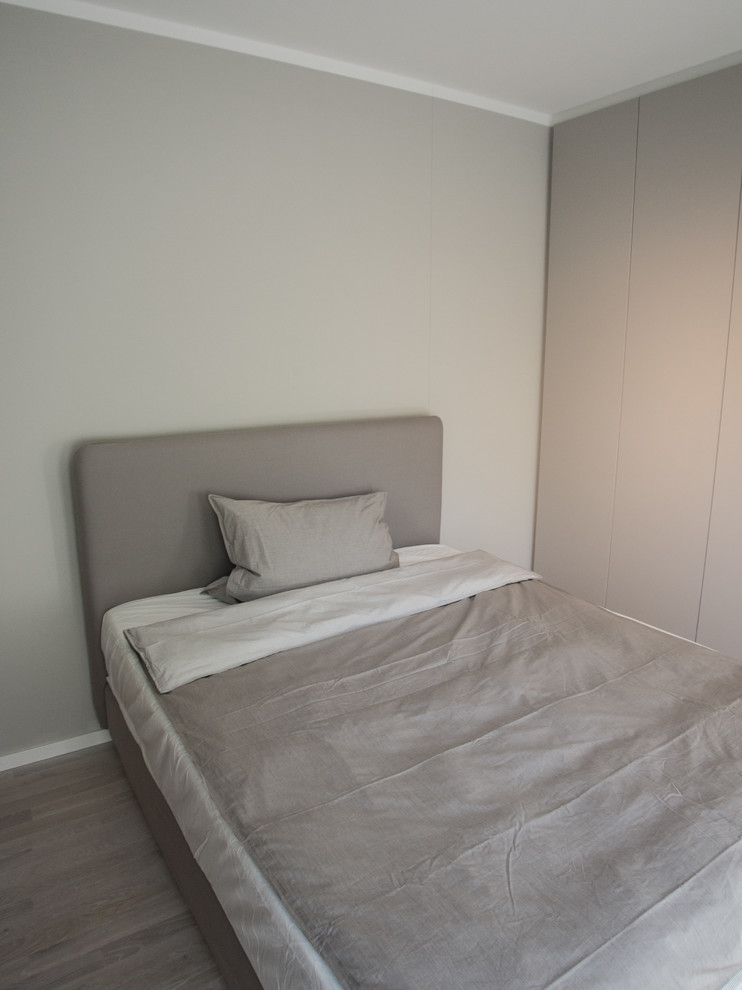 This is an example of a small contemporary loft-style bedroom in Munich with grey walls, light hardwood floors and grey floor.
