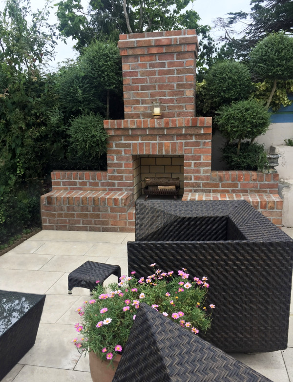 Medium sized contemporary back patio in Dublin with a fireplace, natural stone paving and no cover.