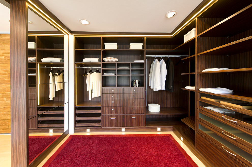 Large midcentury gender-neutral walk-in wardrobe in Stuttgart with open cabinets and beige cabinets.