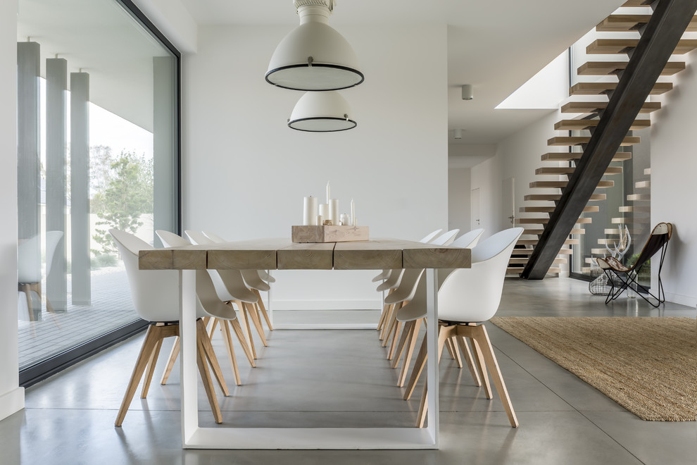 This is an example of a large modern dining room in Other with white walls, concrete floors and grey floor.