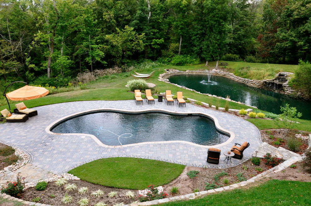 Inspiration for an expansive transitional backyard custom-shaped pool in Cincinnati with natural stone pavers and a hot tub.