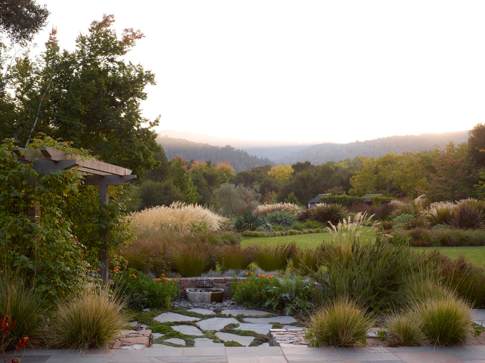 This is an example of an expansive country backyard garden in San Francisco with a garden path and natural stone pavers.