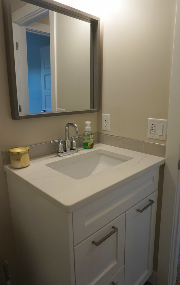 Photo of a small transitional powder room in Calgary with shaker cabinets, white cabinets, beige walls, medium hardwood floors, an undermount sink and quartzite benchtops.