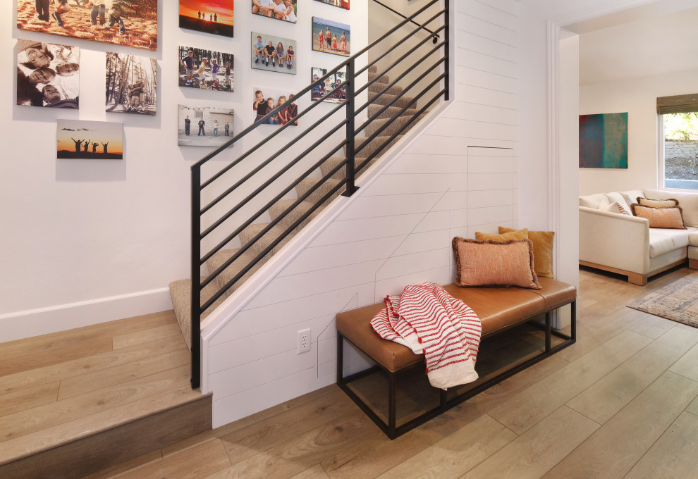 Photo of a small modern carpeted l-shaped staircase in Orange County with carpet risers, metal railing and planked wall panelling.