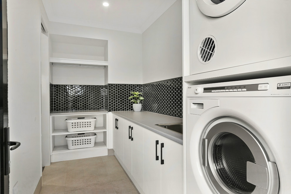 Design ideas for a contemporary dedicated laundry room in Other with flat-panel cabinets, white cabinets, grey walls, a stacked washer and dryer, beige floor and grey benchtop.