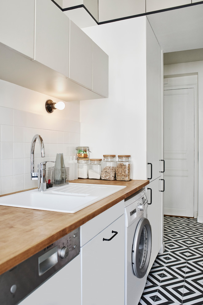 This is an example of a mid-sized contemporary single-wall separate kitchen in Le Havre with an undermount sink, beaded inset cabinets, white cabinets, wood benchtops, white splashback, ceramic splashback, stainless steel appliances, ceramic floors, no island and black floor.