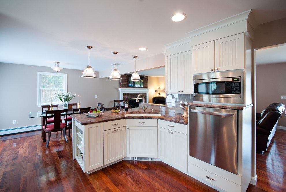 Design ideas for a large traditional u-shaped eat-in kitchen in Providence with an undermount sink, shaker cabinets, white cabinets, granite benchtops, beige splashback, subway tile splashback, stainless steel appliances, a peninsula and medium hardwood floors.