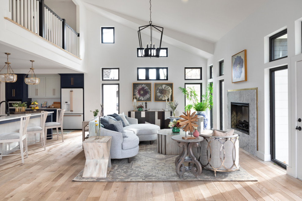 Transitional open concept living room in Kansas City with white walls, light hardwood floors, a standard fireplace, a stone fireplace surround, no tv, beige floor and vaulted.