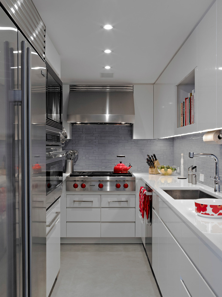 Contemporary u-shaped separate kitchen in New York with stainless steel appliances, an undermount sink, flat-panel cabinets, white cabinets, grey splashback and mosaic tile splashback.