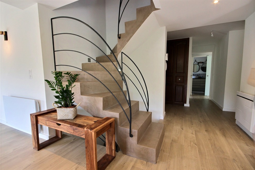 Mid-sized beach style concrete curved staircase in Nice with concrete risers and metal railing.