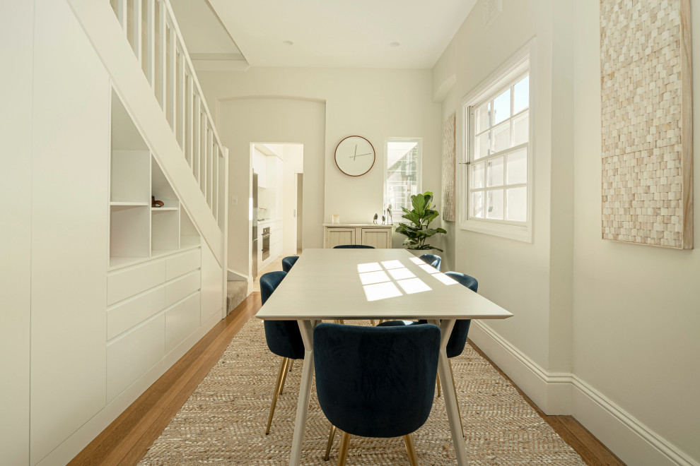 Design ideas for a contemporary open plan dining in Sydney with white walls, light hardwood floors and a standard fireplace.