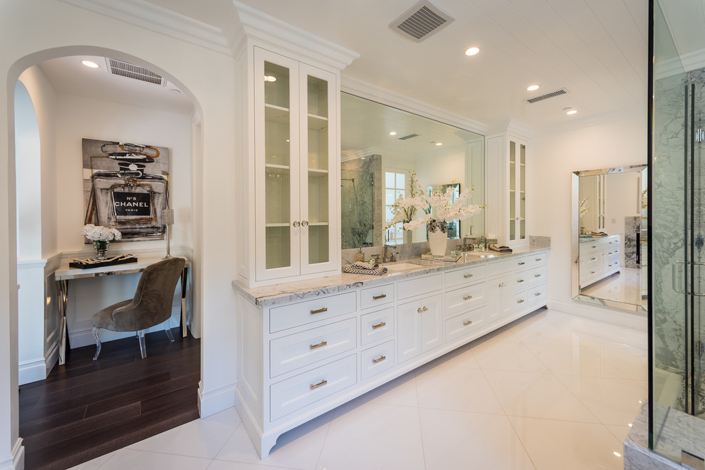 This is an example of a large transitional master bathroom in Los Angeles with shaker cabinets, white cabinets, an undermount tub, a corner shower, gray tile, stone slab, white walls, porcelain floors, an undermount sink, marble benchtops, white floor, a hinged shower door and grey benchtops.