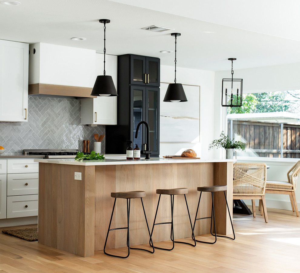 Inspiration for a mid-sized beach style l-shaped eat-in kitchen in Dallas with a single-bowl sink, shaker cabinets, light wood cabinets, quartz benchtops, grey splashback, porcelain splashback, stainless steel appliances, light hardwood floors, with island, brown floor and white benchtop.