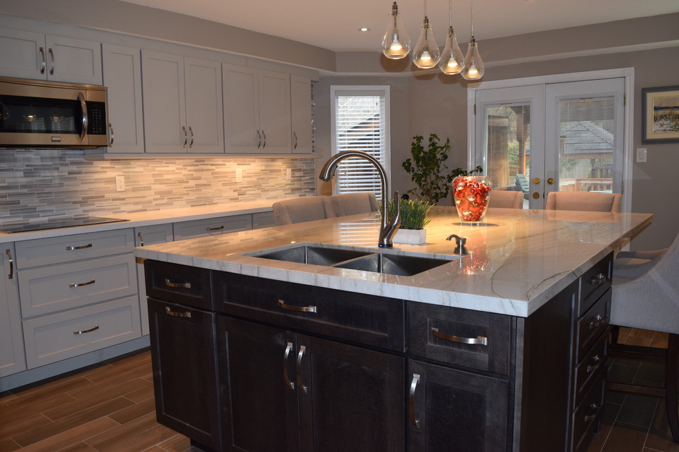 Mid-sized transitional l-shaped eat-in kitchen photo in Toronto with an undermount sink, shaker cabinets, gray cabinets, quartzite countertops, multicolored backsplash, subway tile backsplash, stainless steel appliances and an island