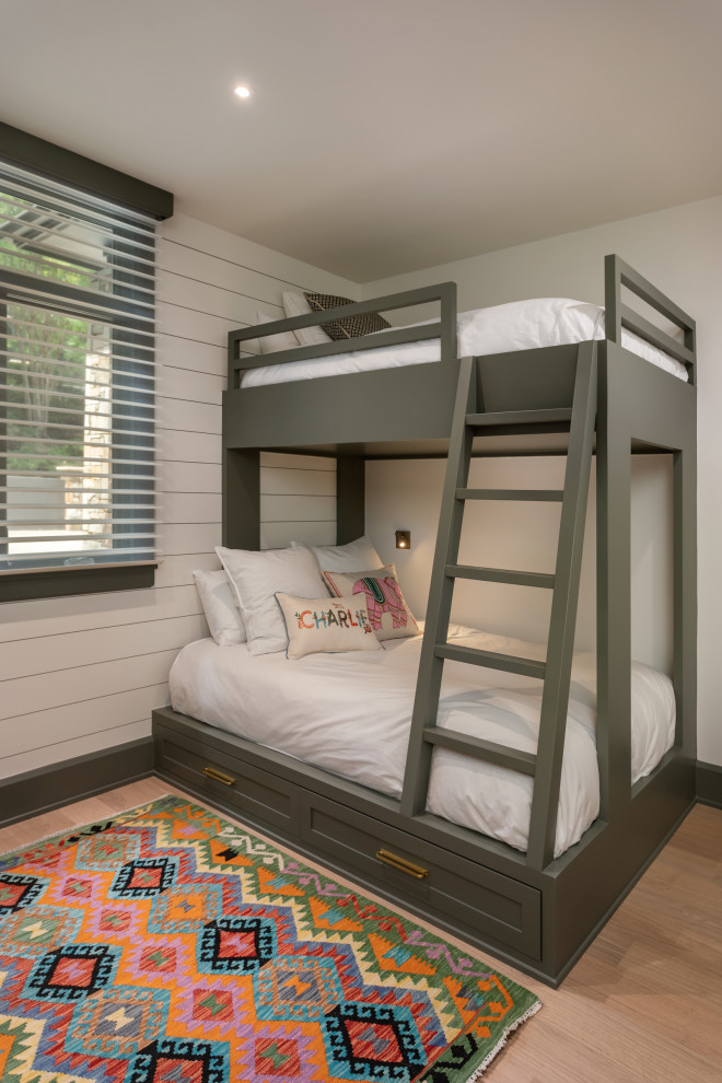 This is an example of a mid-sized transitional gender-neutral kids' bedroom for kids 4-10 years old in Other with white walls, light hardwood floors and beige floor.
