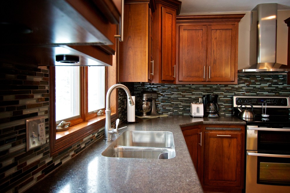 Mid-sized l-shaped light wood floor open concept kitchen photo with an undermount sink, shaker cabinets, dark wood cabinets, laminate countertops, multicolored backsplash, glass tile backsplash, stainless steel appliances and an island