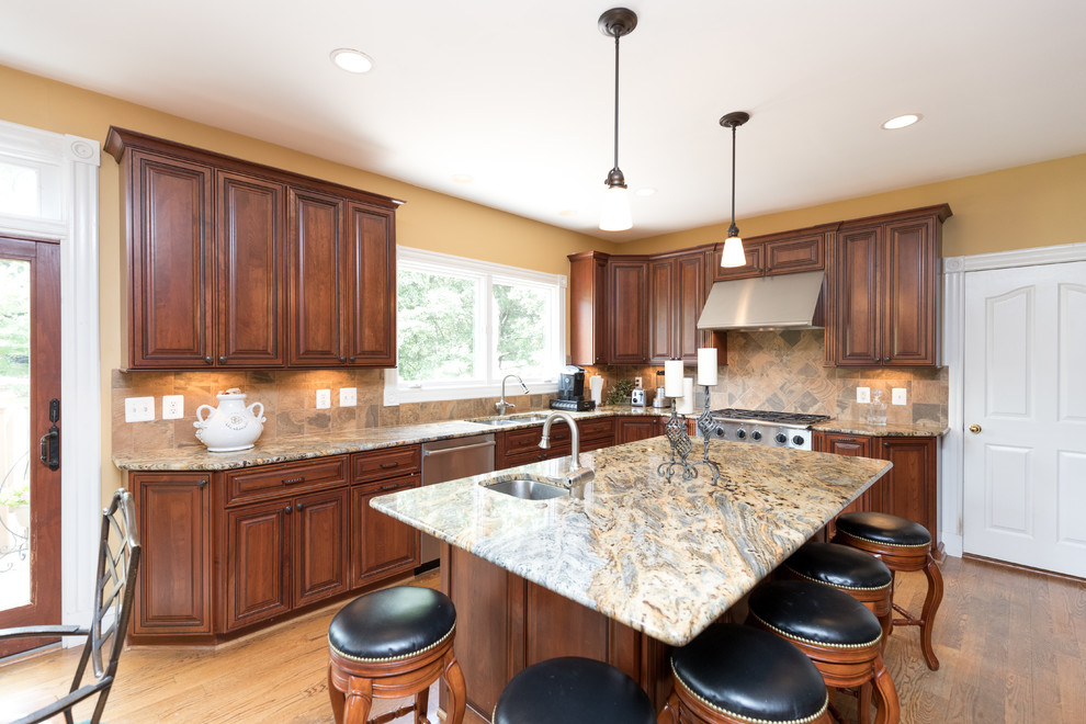 Mid-sized transitional u-shaped medium tone wood floor eat-in kitchen photo in DC Metro with an undermount sink, raised-panel cabinets, dark wood cabinets, granite countertops, beige backsplash, stone tile backsplash, stainless steel appliances and an island