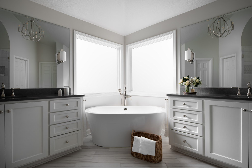 Photo of a medium sized classic ensuite bathroom in Kansas City with recessed-panel cabinets, white cabinets, a freestanding bath, an alcove shower, white tiles, ceramic tiles, grey walls, porcelain flooring, a submerged sink, engineered stone worktops, grey floors, a hinged door, brown worktops, a shower bench, a single sink, a built in vanity unit and a vaulted ceiling.
