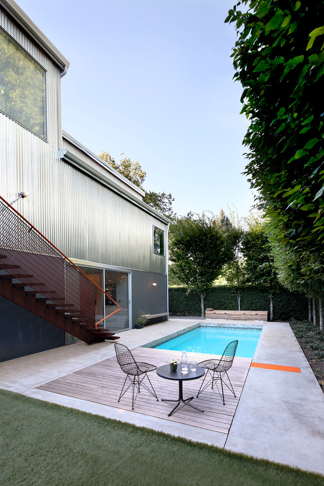 This is an example of a mid-sized industrial backyard rectangular lap pool in Seattle with concrete slab.